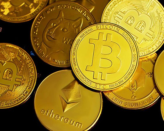 several gold crypto coins on top of a black surface